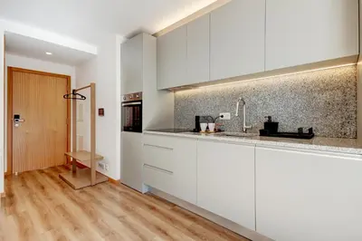 a kitchen with white cabinets and a wooden floor at Blue Hotel Oporto in Porto