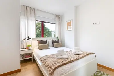 a white bedroom with a large bed with a window at Boavista Residence T3 in Porto