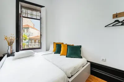 two beds in a white room with a window at Terraced Apartment in the Heart of Porto - Free Parking in Porto