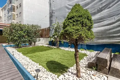 a small garden with trees and rocks in front of a building at Porto Inlapa Studio RC in Porto