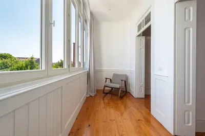 a white hallway with a chair and a window at Bonfim 241 Family House in Porto