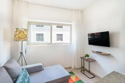 a white bedroom with a bed and a lamp on a night stand at VIVA Elias Sunset Apartment Gaia in Vila Nova de Gaia