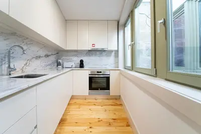 a kitchen with white cabinets and a wooden floor at Lifestyle at Porto by Upperground in Porto