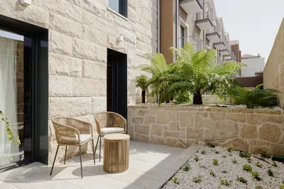 a patio with a table and chairs in front of a building at Porto River Soul Hotel in Vila Nova de Gaia
