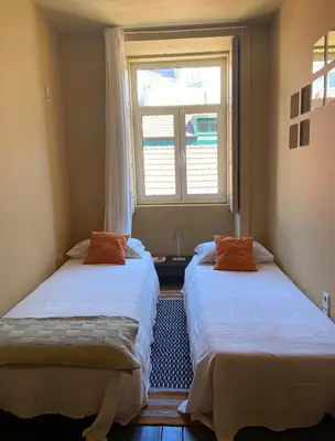 two beds in a room with a window at Sunny Apartment in Porto