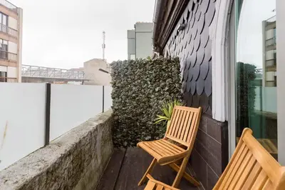 a wooden chair sitting on a balcony next to a window at Typical Oporto House in Porto