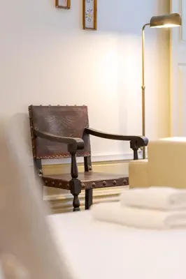 a wooden chair sitting in a room next to a lamp at Cedofeita Vintage House DA'Home in Porto