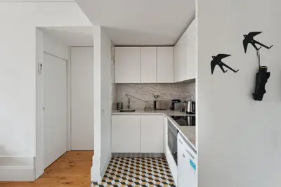 a kitchen with white cabinets and a black and white checkered floor at GuestReady - Explore Porto from a prime location in Porto