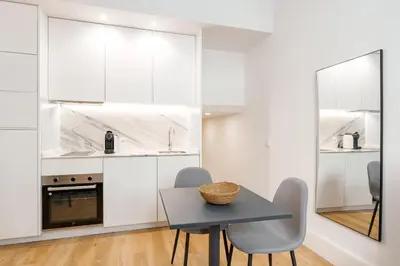 a kitchen with white cabinets and a table and chairs at VIVA João IV Residence Studios in Porto