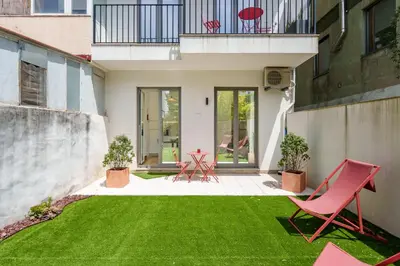 a yard with red chairs and a green lawn at VIVA João IV Residence Studios in Porto