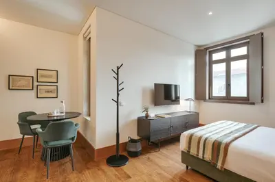 a bedroom with a bed and a table and a tv at Republica 144 Apartamentos by DA'Home in Porto