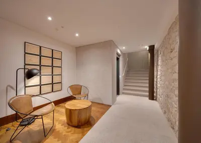 a hallway with two chairs and a table and a stone wall at Republica 144 Apartamentos by DA'Home in Porto