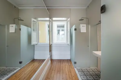 a bathroom with white walls and a window and wooden floors at GuestReady - Vereda Downtown Apartments in Porto