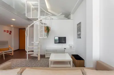 a living room with white walls and a staircase at Rosario Duplex in Porto
