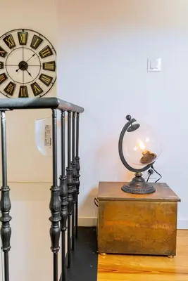 a clock and a lamp on a chest next to a table at Cozy Stay w/ AC and View in Porto