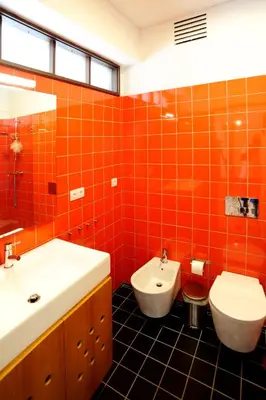 an orange tiled bathroom with a sink and a toilet at Baron Omega in Porto