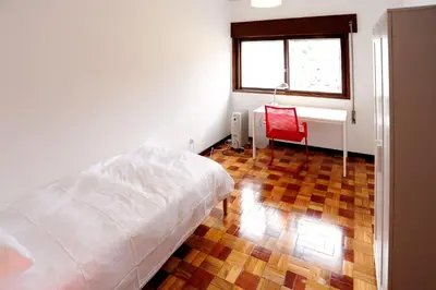 a bedroom with a bed and a window and a red chair at Omega White in Porto