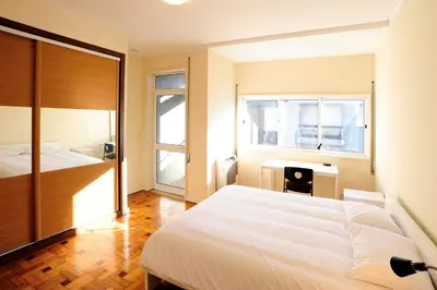 a bedroom with a bed and a desk and window at School Santos Pousada in Porto