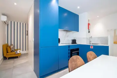 a kitchen with blue cabinets and a table and chairs at Bom Retiro's Delight by LovelyStay in Porto