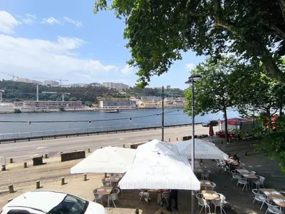 a group of tables with umbrellas next to a river at Sailor's House 3 - Casa dos Bibos in Porto