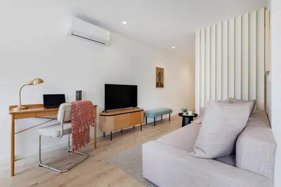 a living room with a couch and a desk with a tv at The Light Loft @ BoaVista Flats in Porto