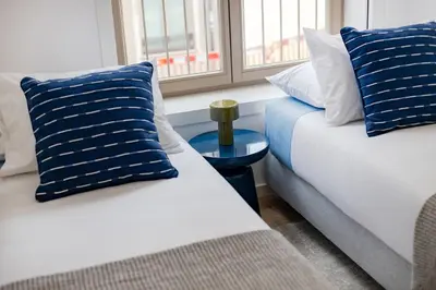 two beds with blue and white pillows in a room at The Light Loft @ BoaVista Flats in Porto
