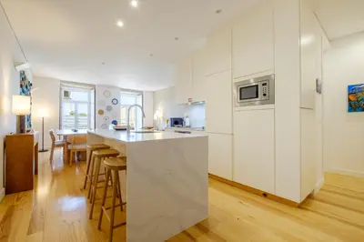 a kitchen with white cabinets and a kitchen island with bar stools at Porto Cedofeita Urban Charm Residence in Porto