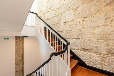 a staircase with a stone wall and wooden floors at Large Studio with City Views in Porto