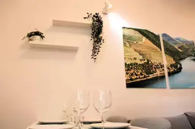 a table with wine glasses and a picture on the wall at Alegria Street Flat in Porto