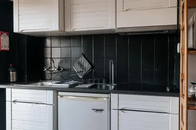 a kitchen with white cabinets and a black tiled wall at Palácio de Cristal, Porto Apartment by Mycelia in Porto