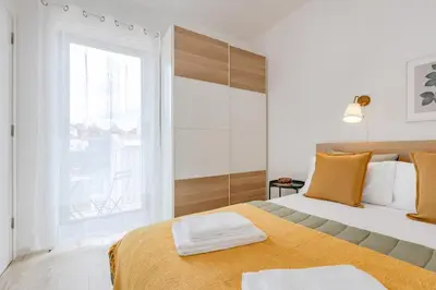 a kitchen with white cabinets and a wooden table at The Morning Light @ BoaVista Flats in Porto
