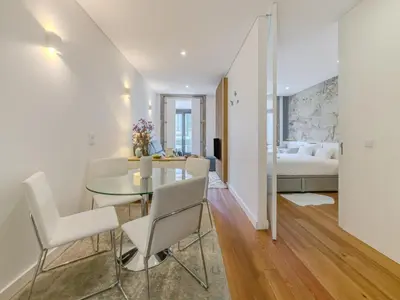 a dining room with a glass table and white chairs at Almada Comfy in Porto
