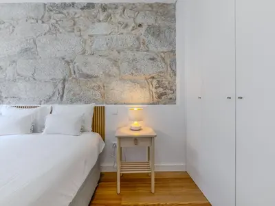 a bedroom with a bed and a table with a lamp at Almada Comfy in Porto