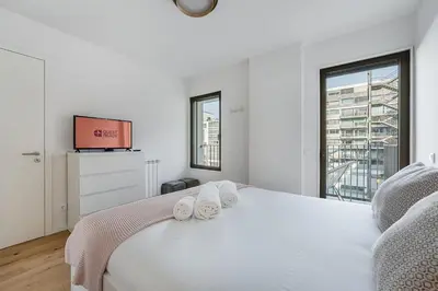 a white bedroom with a bed and a tv at GuestReady – Steps from Estádio do Dragão in Porto