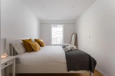 a bedroom with a white bed with yellow pillows and a window at GuestReady - Relaxing Getaway Near Porto in Vila Nova de Gaia