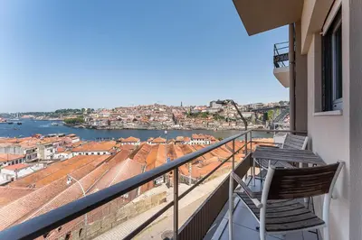 a balcony with two chairs and a view of the water at GuestReady - Lovely home with river view in Vila Nova de Gaia