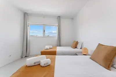 a white room with two beds and a window at GuestReady - Lovely home with river view in Vila Nova de Gaia