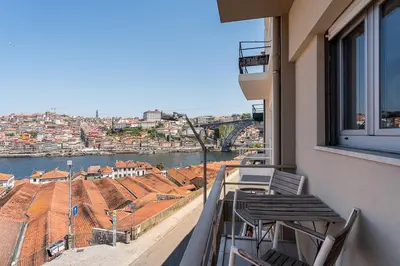 a balcony with chairs and a view of a city at GuestReady - Lovely home with river view in Vila Nova de Gaia