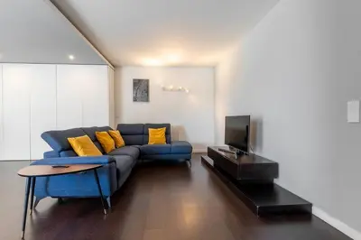 a living room with a blue couch and a tv at Spacious 2BR en suite, downtown Porto in Porto
