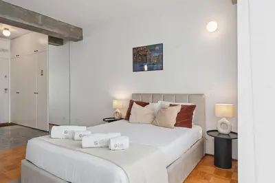 a white bedroom with two beds and two lamps at GuestReady – A welcoming space to unwind in Porto