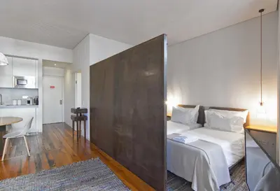 a white bedroom with a white bed and a chair at Casas do Rivoli in Porto