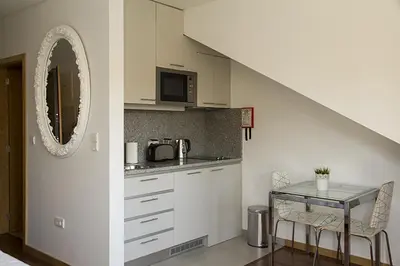 a kitchen with white cabinets and a table with a mirror at Clerigos View in Porto