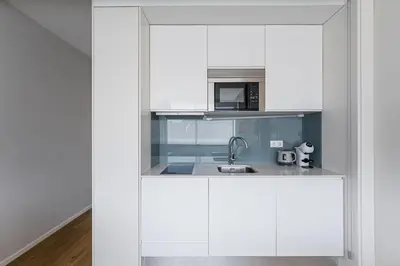 a white kitchen with a sink and a microwave at Trindade Duo Apartments in Porto