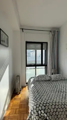 a bedroom with a bed and a large window at Trindade Apartment in Porto