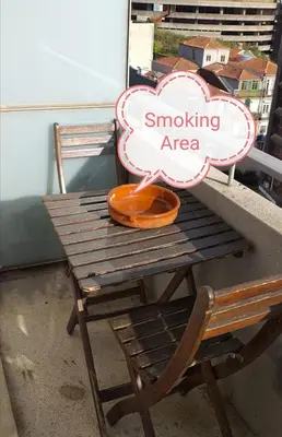a wooden table and chair on a balcony with a smoking area sign at Trindade Apartment in Porto