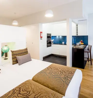 a bedroom with a large bed and a kitchen at Oportolazaro Premium Downtown Porto in Porto