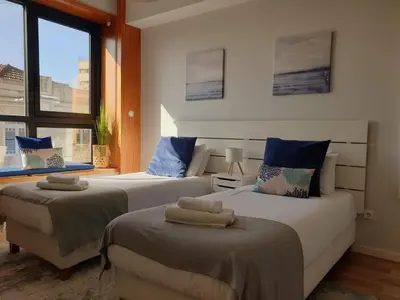 a bedroom with two beds and a large window at Charming Apartment in the Heart of Historic Porto in Porto
