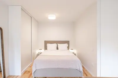 a white bedroom with a bed and a large mirror at VIVA Central Downtown Studio in Porto