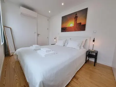 a white bed in a white room with a picture on the wall at Ponte & Morro Apartment in Vila Nova de Gaia