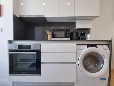 a kitchen with a washing machine and a microwave at Ponte & Morro Apartment in Vila Nova de Gaia